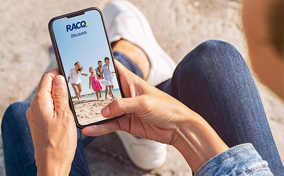 racq-discounts-app-holding-phone